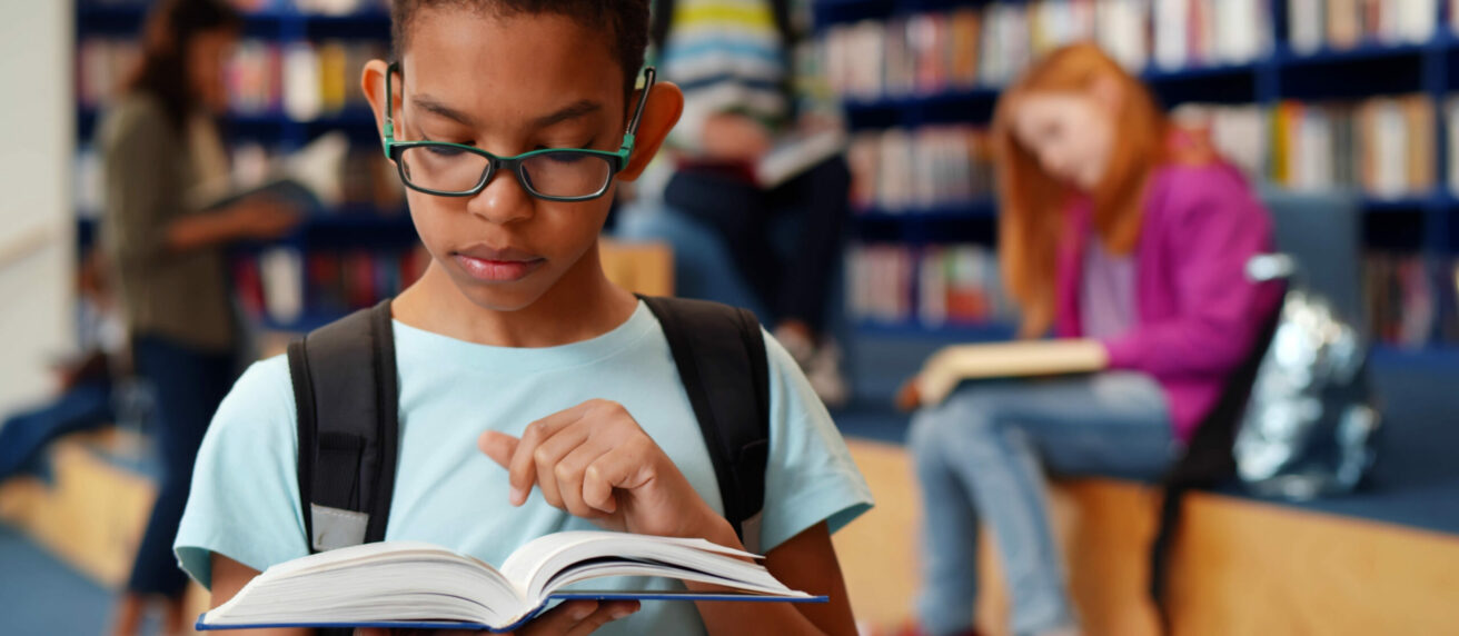 Junge mit Myopie Brille liest Buch